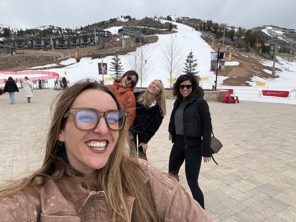 Four friends taking a selfie at the base of a ski mountain
